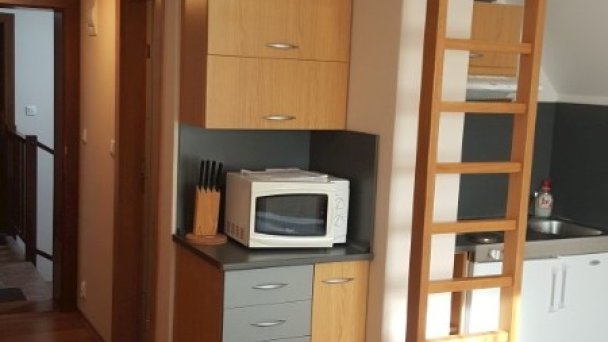 Pohľad od postele jednoizbového apartmánu na poschodí a rebrík do podkrovnej  časti