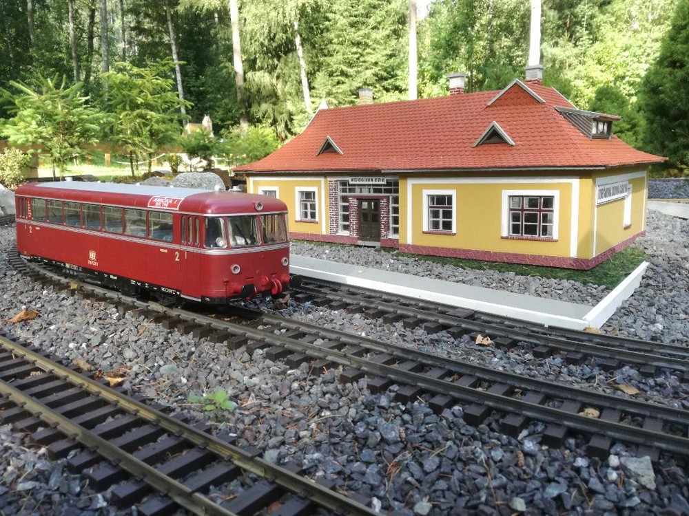 Miniatúra železničnej stanice pred ktorou stojí červený vláčik