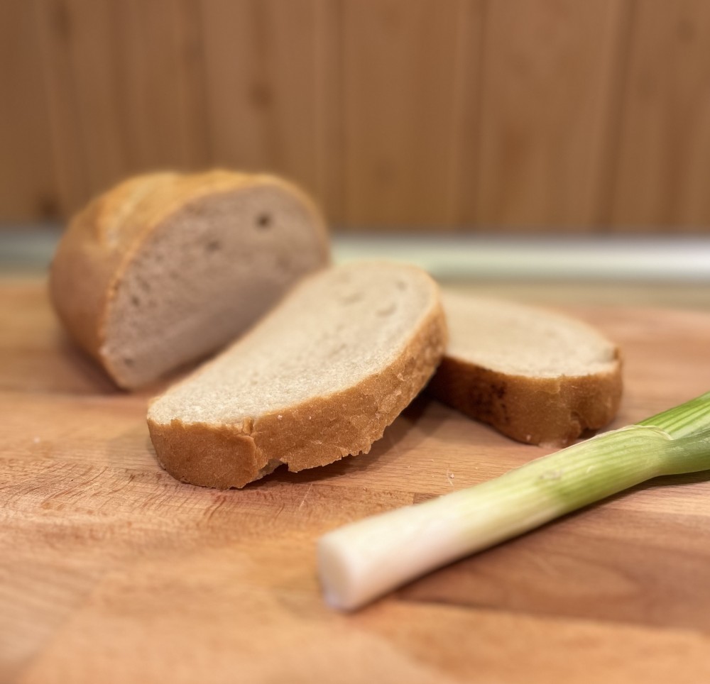 domaci chlieb na drevenej tácke s jarnou cibulkou