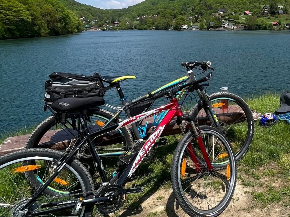 Dva bicykle opreté o lavičku s výhľadom na jazero a okolité hory.