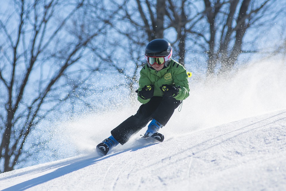 malý chlapec lyžuje dole kopcom na zasneženom svahu